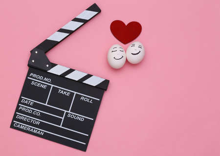 romantic movie. Clapperboard and enamored face eggs with a heart on a pink background. top viewの写真素材