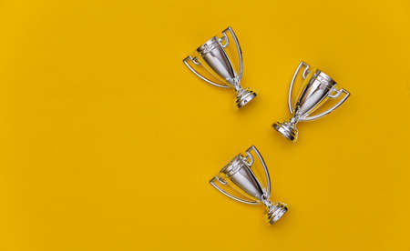 Mini silver sports championship cups on yellow pastel background. copyspace. Sport minimalism. top...