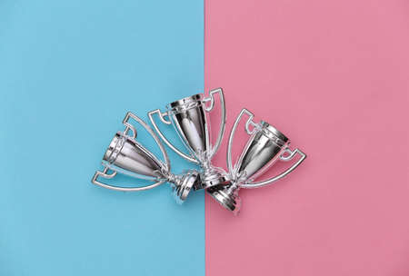 Mini silver sports championship cups on a blue-pink pastel background. Sport minimalism. top viewの写真素材