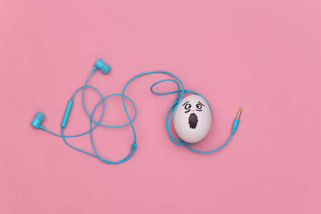 Puzzled egg face with tangled headphones on pink pastel backgroundの写真素材