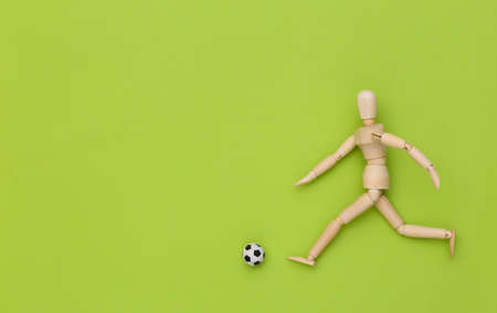 Wooden puppet playing soccer with a ball on green backgroundの写真素材