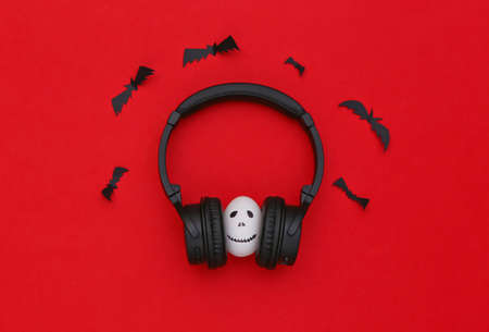 Halloween theme. Egg with hand drawn scary ghost face listen music in headphones on red backgroundの写真素材