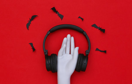 Mannequin hand and stereo headphones with bats on red backgroundの写真素材
