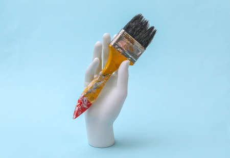 The mannequin's white hand holds a brush on a light blue background.の写真素材