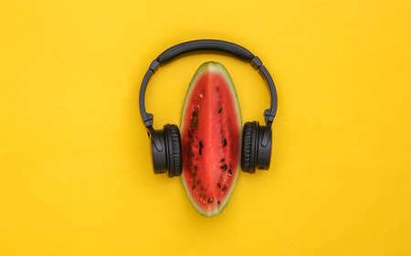 Slice of ripe watermelon and stereo headphones on yellow background. summer fun. top view. flat lay