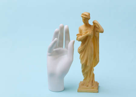 Plaster hand and antique statue on a blue background.の写真素材