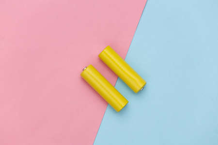 Two yellow AA batteries on pink blue pastel background. top viewの写真素材