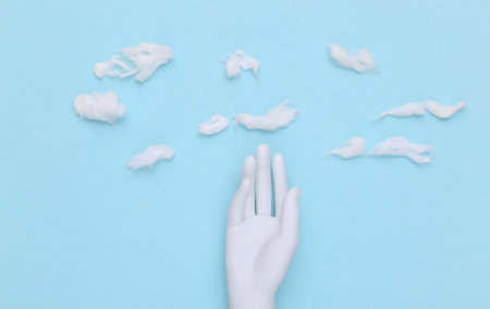 Mannequin hand on hand made sky background with cloudsの写真素材