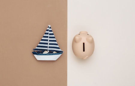 Sailboat and piggy bank on brown beige background. travel concept. top view