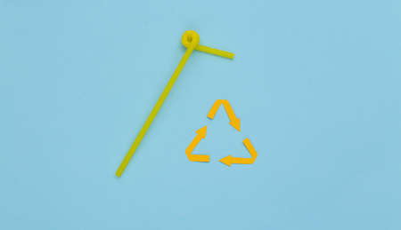Recycled arrows sign and Plastic cocktail straws on blue background. Eco concept. top view