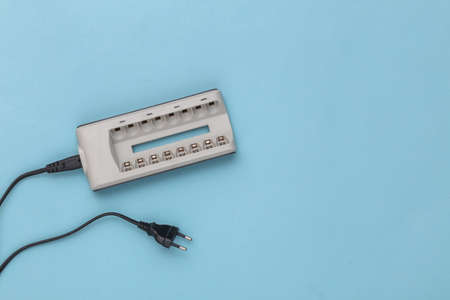 Charger for batteries on blue background. top view