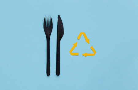 Recycled arrows sign, plastic fork and knife on blue background. Eco concept. top viewの写真素材