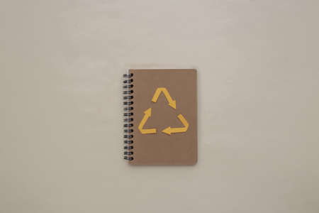Recycled arrows sign and notebook on beige background. Eco concept. top viewの写真素材
