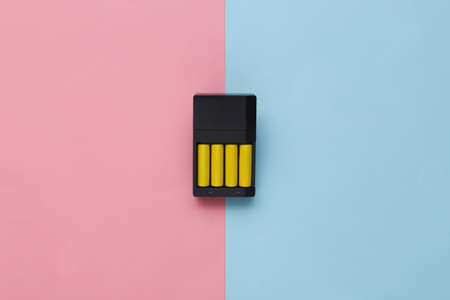 Charger with aa type batteries on pink blue background. top viewの写真素材
