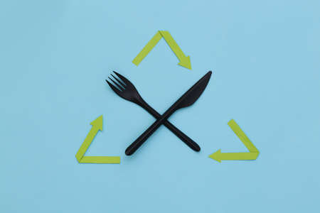 Recycled arrows sign, plastic fork and knife on blue background. Eco concept. top view