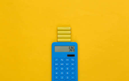 Calculator and batteries on yellow background. top viewの写真素材
