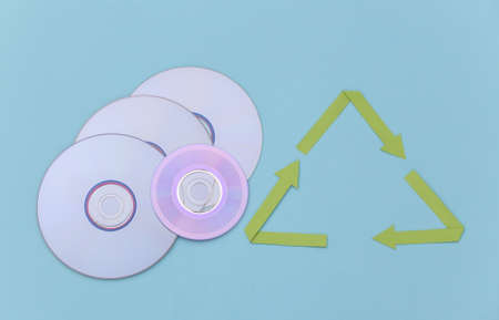 Recycled arrows sign and CD discs on blue background. top view