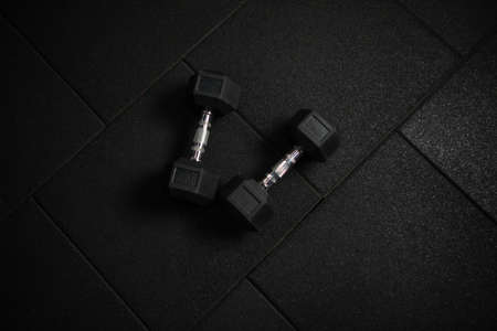 Metal rubberized dumbbells on a dark black floor. Bodybuilding and Fitnessの写真素材