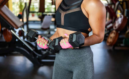 Sport Woman trains biceps with dumbbells in her hands in the gymの写真素材