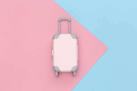 travel concept. Mini plastic travel suitcase on pink blue pastel background. minimal style. top...