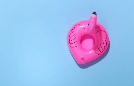 Inflatable pink flamingo on blue sunny background. Summer vacation concept. minimalism. top view. copy spaceの写真素材