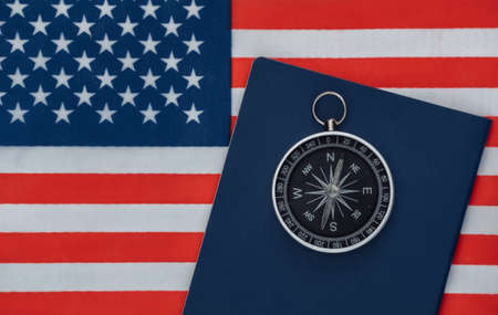 Compass and passport on USA flag close up. top view