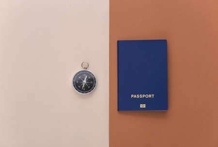 Minimalist travel flat lay. Compass and passport on beige brown background. top viewの写真素材