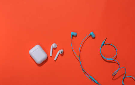 Wireless earbuds with charging case and classic wired earbuds on bright orange backgroundの写真素材
