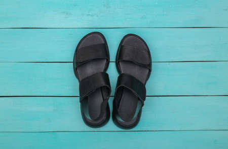 Feminine leather black sandals on blue wooden background. top viewの写真素材