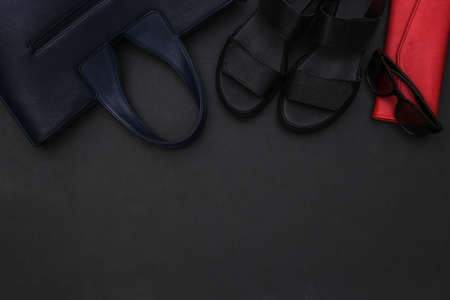 Women's accessories on black background with copy space. Sandals, bag, leather wallet, headphones and sunglasses. top viewの写真素材