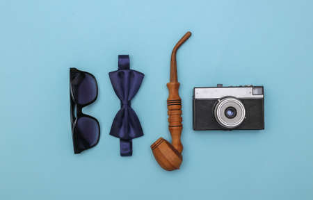 Smoking pipe and bow tie, sunglasses and camera on a blue background. Gentleman's accessories. top...