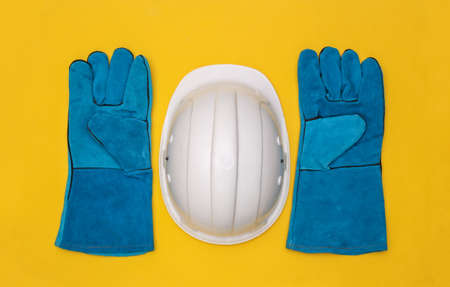 Work gloves and construction safety helmet on yellow background. top viewの写真素材
