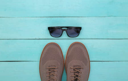 Men's shoes and sunglasses on blue wooden background. top viewの写真素材