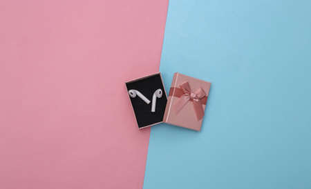 New wireless headphones in a gift box on a blue pink pastel background. top view