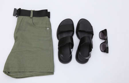 Shorts and leather sandals, sunglasses on a white background. Women's clothing and accessories. top view. flat layの写真素材