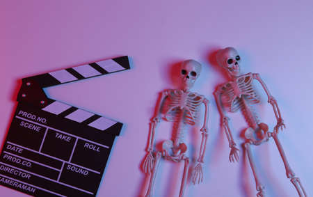 Movie clapperboard with skeletons in gradient neon red-blue light. Halloween scary movieの写真素材