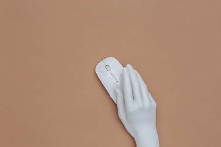 The mannequin's white hand holding pc mouse on brown background. top viewの写真素材