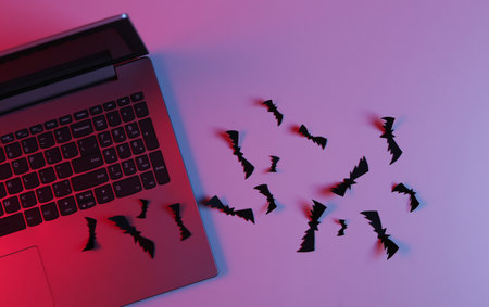 Laptop and Flying paper cut bats in neon blue pink light. Halloween themeの写真素材