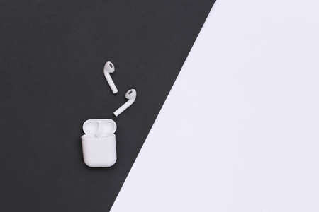 Small earbuds with charger case on black white background. top view. copy space