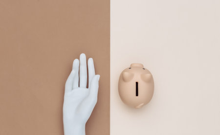 Piggy bank and mannequin hand on brown beige background. Flat lay minimalism. top view.