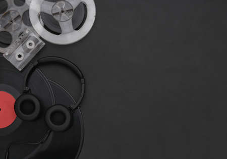 Retro vinyl records, audio magnetic reel, audio cassette and stereo headphones on black background. copyspace. top viewの写真素材