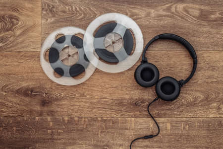 Retro audio magnetic reel and stereo headphones on wooden background. top view. flat layの写真素材