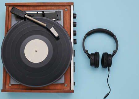 Retro vinyl player and stereo headphones on blue background. top view. flat layの写真素材