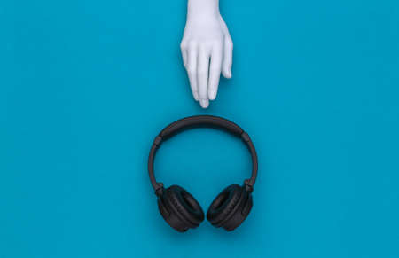 Mannequin's white hand and stereo headphones on blue background. top viewの写真素材