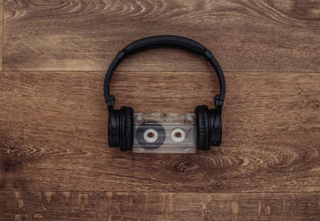 Wireless stereo headphones with audio cassette on a wooden background. top viewの写真素材