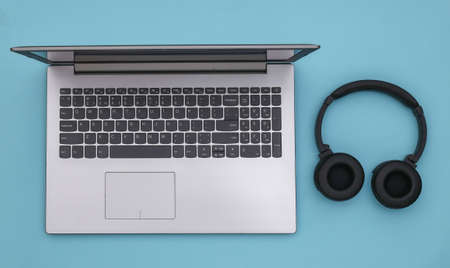 Laptop and wireless stereo headphones on blue background. top view.の写真素材