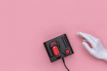 Mannequin hand touching retro joystick on pink background. Top view, minimalismの写真素材