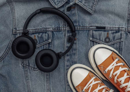 Youth clothing and accessories. Sneakers and headphones on jeans jacket background. top view. flat layの写真素材