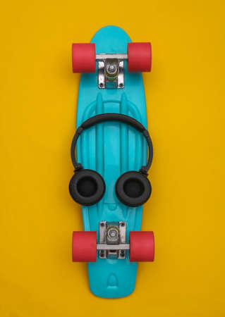 Flat lay composition of youth hipster accessories. Cruiser board and headphones on yellow background. top viewの写真素材