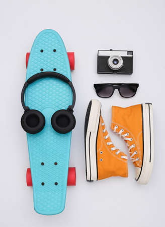 Flat lay composition of youth hipster accessories. Cruiser board, sneakers, headphones, camera and...